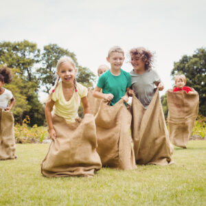 Children having a sack race in park on a sunny day