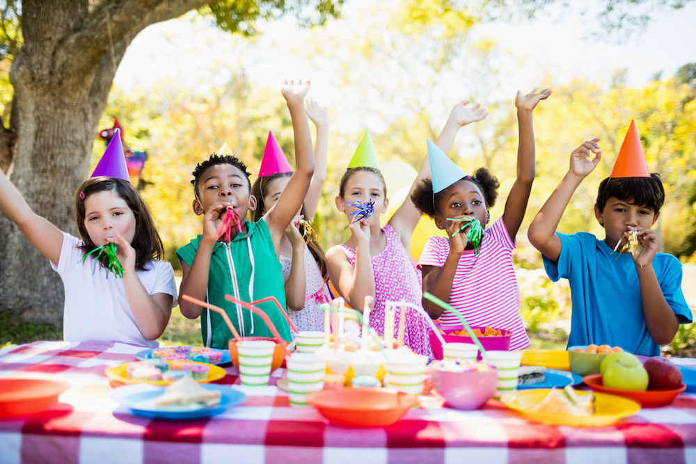 Cute children of different ethnicities having fun during a birthday party on a park.