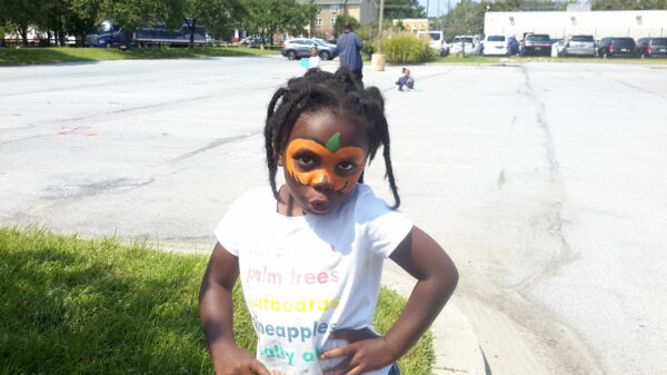 Pretty girl with a pumpkin face painting at a party.