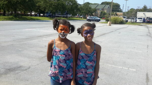 Twin girls with face paintings at a party.