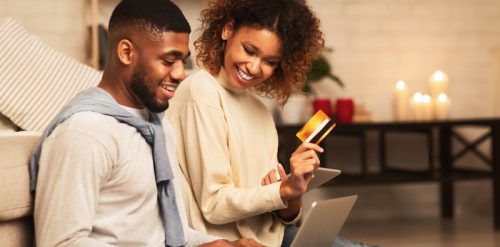 Happy african-american couple looking at laptop and buying online